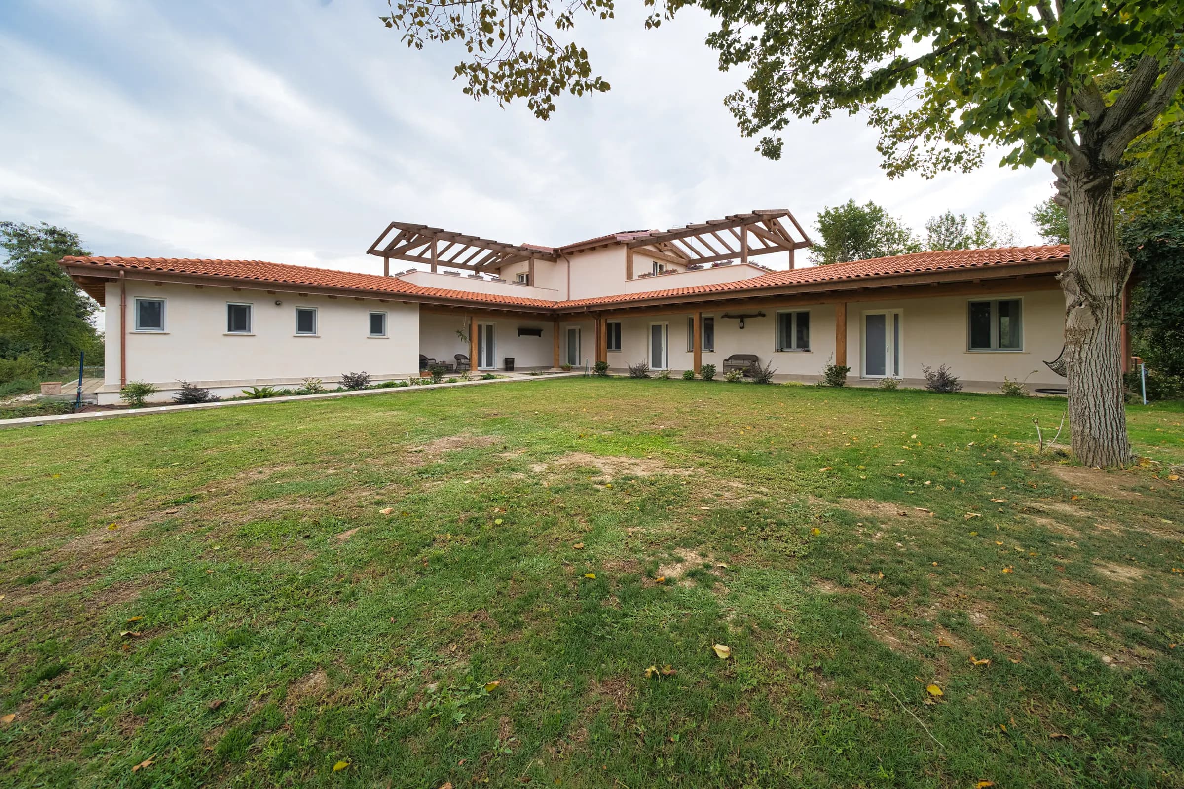 La casa a un piano con il portico in legno, affacciata sul prato